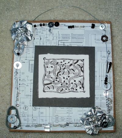Drawing on mat on circuit diagram background, with built in wire frame embellished with found and recycled objects and assorted beads